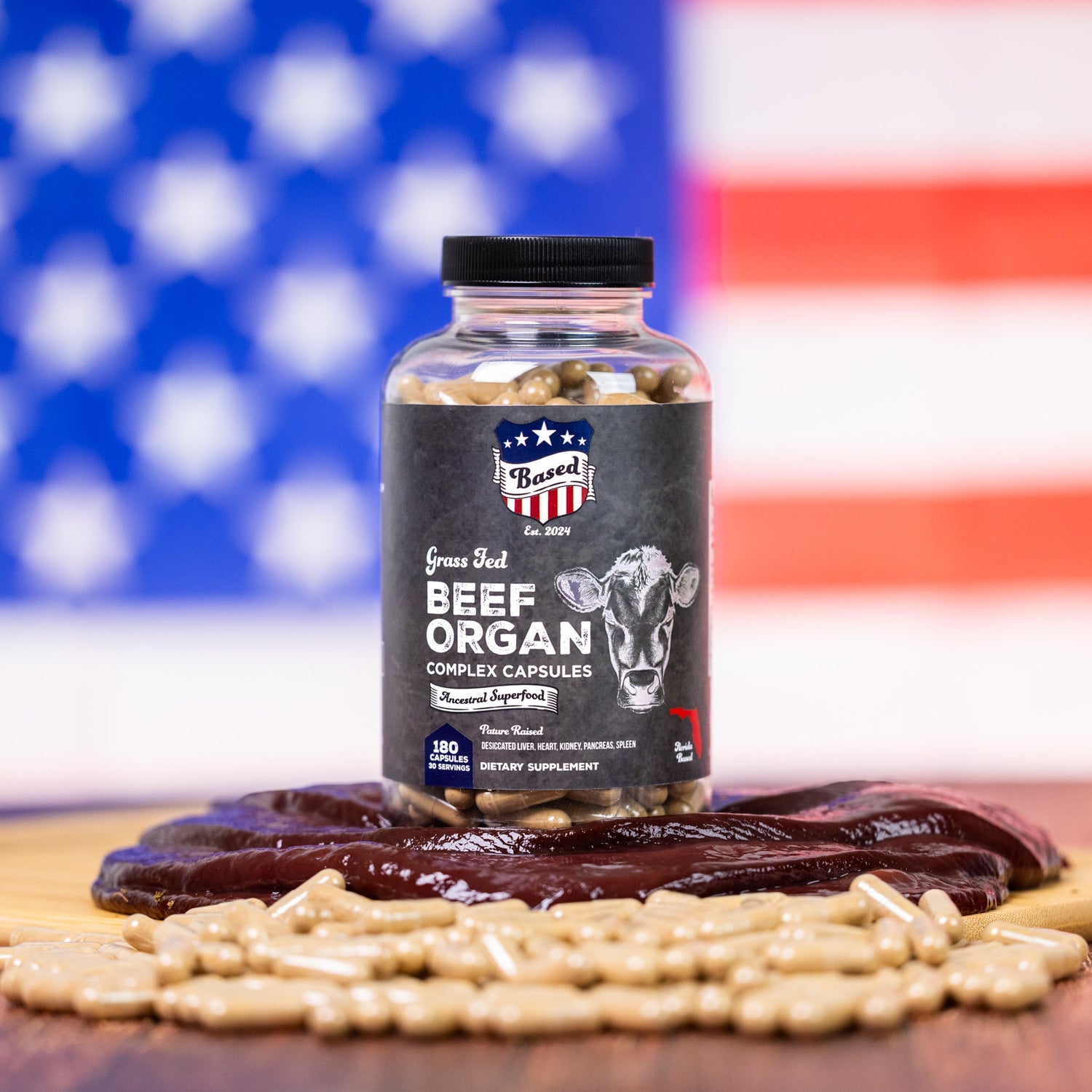 A bottle of Based Beef Organ Multivitamin and liver in front of an American flag